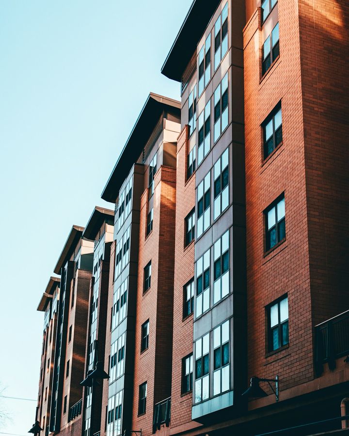 A red brick apartment block with balconies against a pale sky